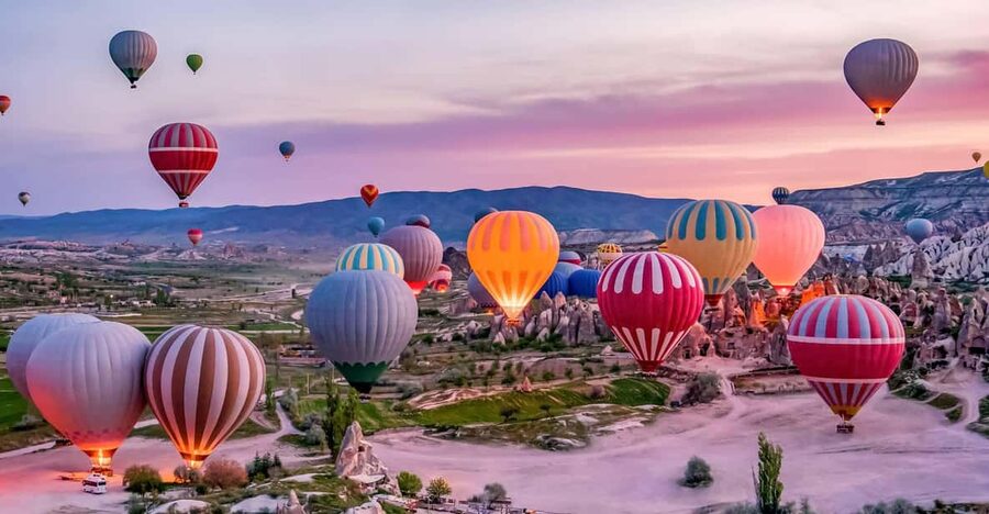 Balloons lifting over the rock cones of Goreme at first light